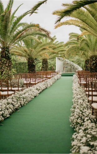 Decoração da entrada dos noivos com um tapete verde e flores brancas