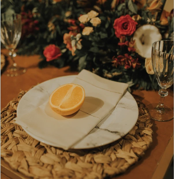 Mesa com um prato e guardanapo em cima do prato e meia laranja