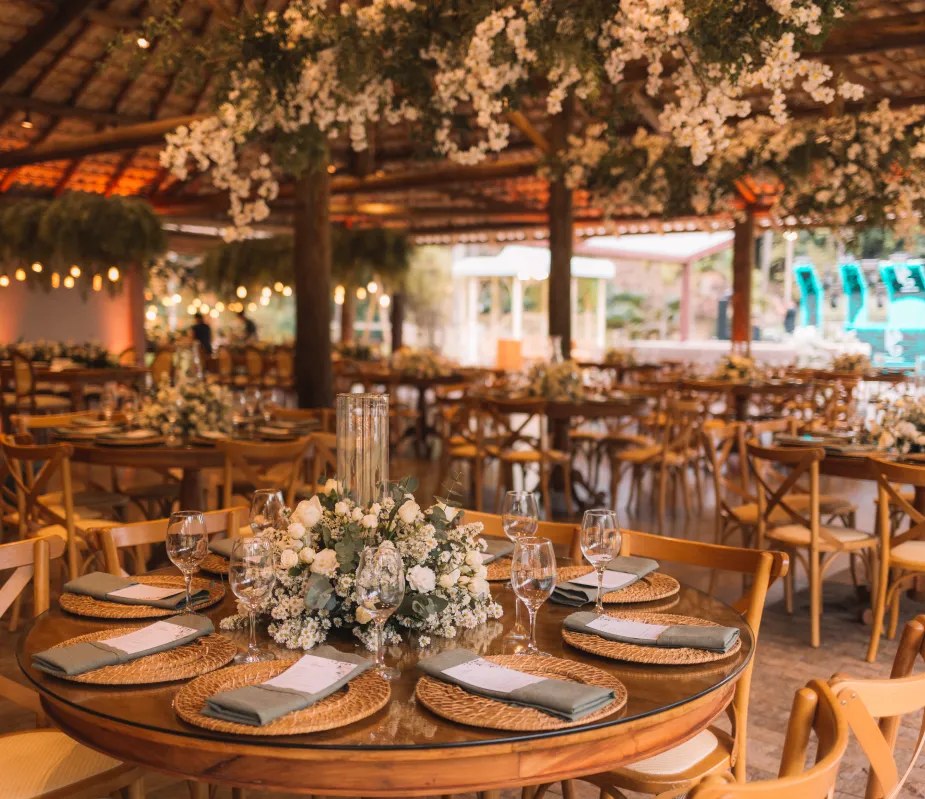 mensa de Jantar redonda amadeirada com pratos e taças e um arranjo floral