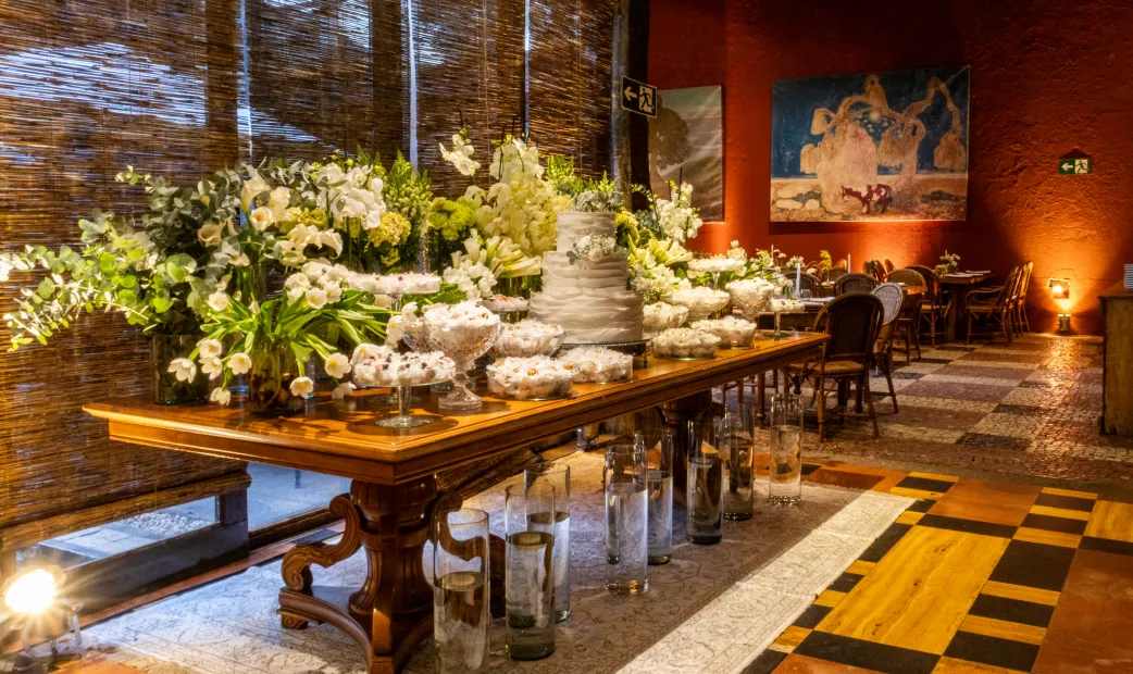 Mesa decorada com arranjos florais, doces e bolo