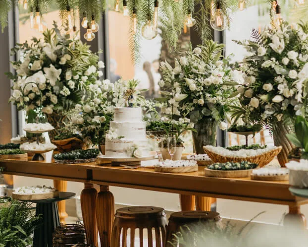 Mesa decorda com bolo e várias flores brancas